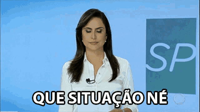 a woman in a white shirt stands in front of a screen that says que situacao ne