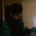 a blurry picture of a person in a green jacket standing in front of a mirror .