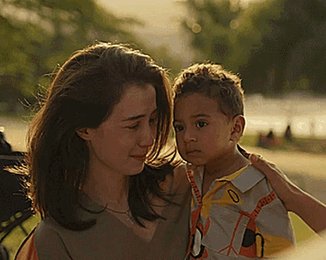 a woman is holding a child who is wearing a shirt with the number 0 on the front