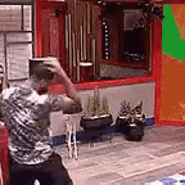a man in a striped shirt is standing in front of a colorful wall in a living room .