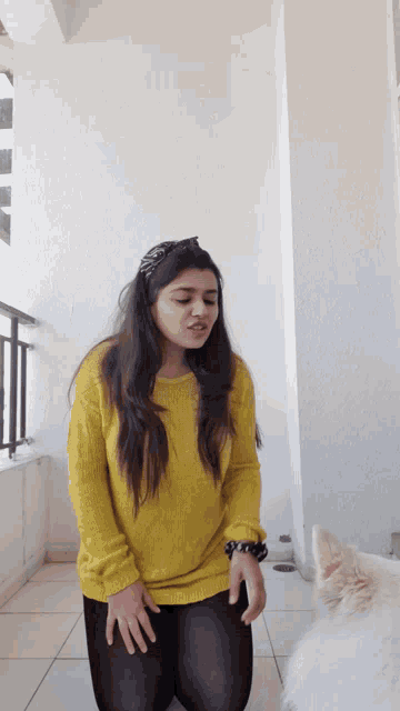 a woman in a yellow sweater and black tights is kneeling down