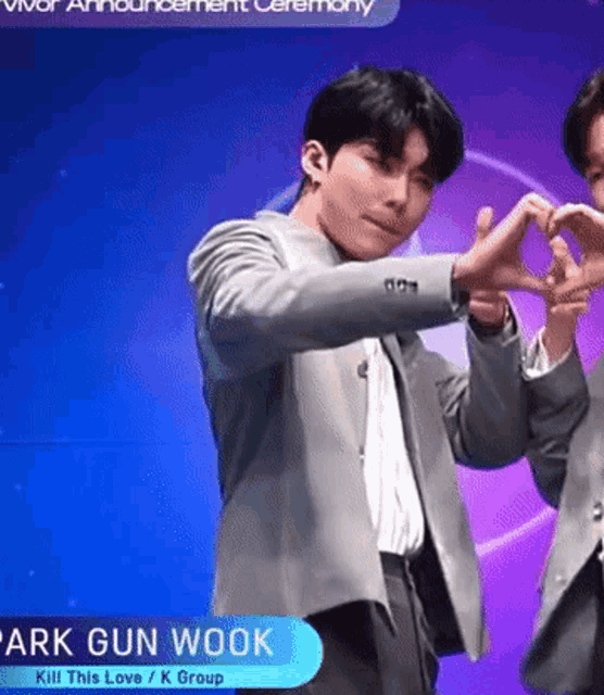 a man in a suit making a heart shape with his hands