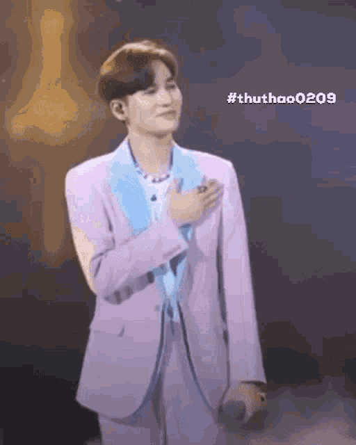 a man in a purple suit is singing into a microphone while standing on a stage .