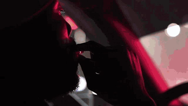 a man smoking a cigarette in a car with a red light behind him