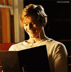 a man wearing headphones is smiling while holding a book .