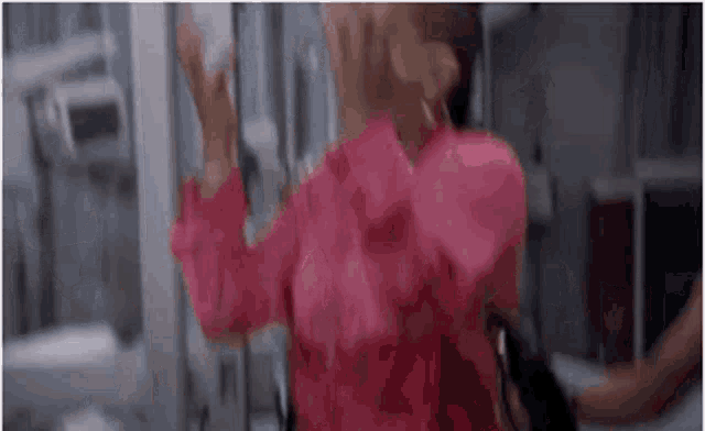 a woman in a pink shirt is standing in front of a window .