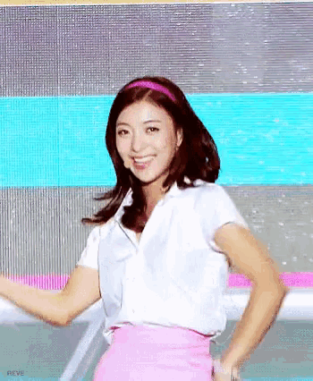 a woman wearing a white shirt and a pink skirt is smiling