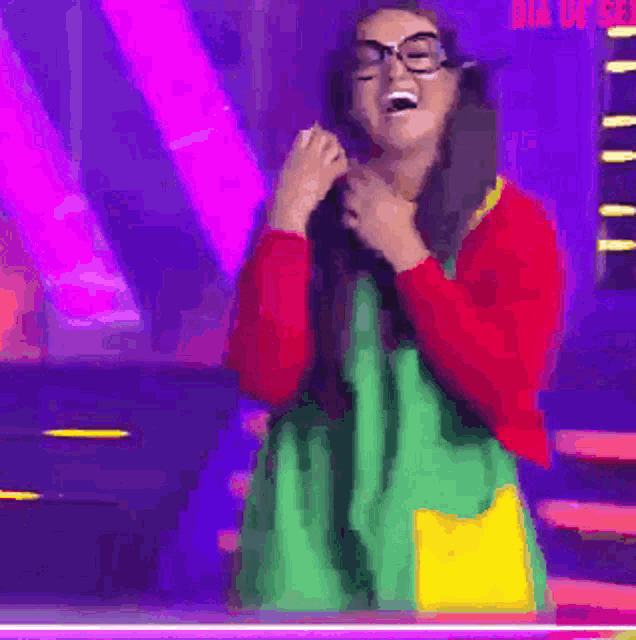 a woman wearing glasses and a green dress is standing on a stage .