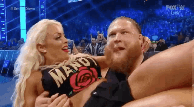 a man is holding a woman in his arms on a wrestling match .