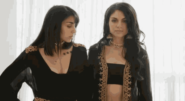 two women are standing next to each other wearing black and gold clothes