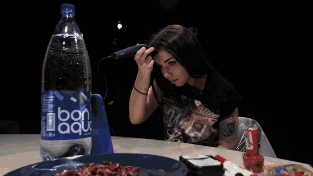 a bottle of bon aqua water sits on a table next to a woman