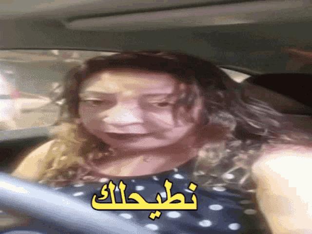 a woman is driving a car with arabic writing on the side