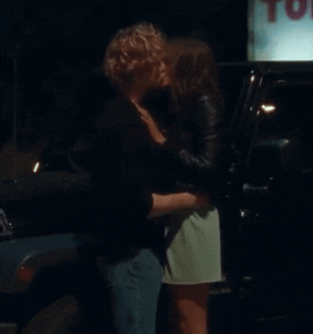 a man and woman kissing in front of a sign that says toyota