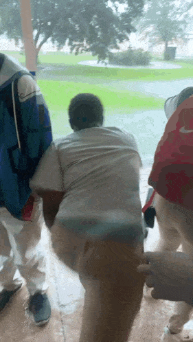 a group of people are standing in the rain and one has a nike hat on