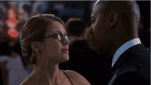 a man and a woman are looking at each other and the woman is wearing glasses
