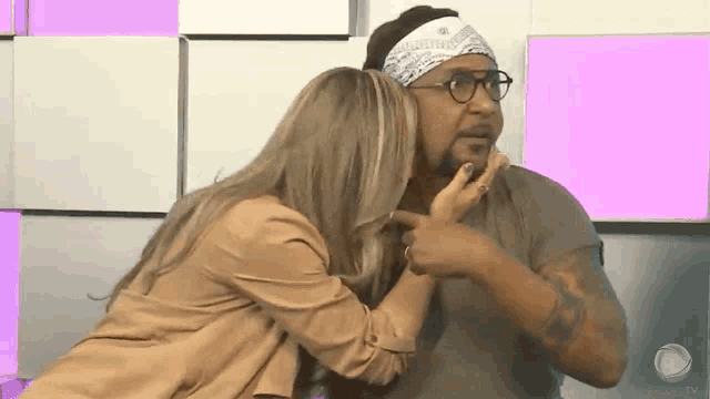 a woman is touching a man 's face while wearing glasses and a headband