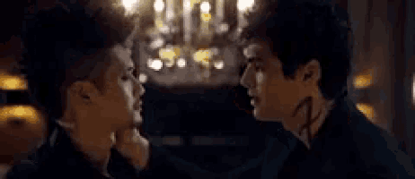 two men are touching each other 's faces in a dark room .