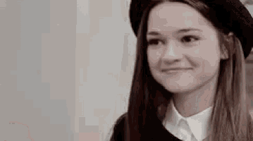 the girl is wearing a black hat and a white shirt .
