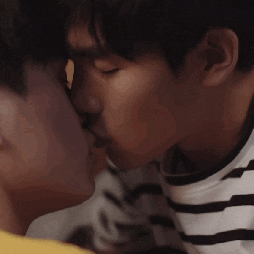 two young men are kissing each other in a close up of their faces .