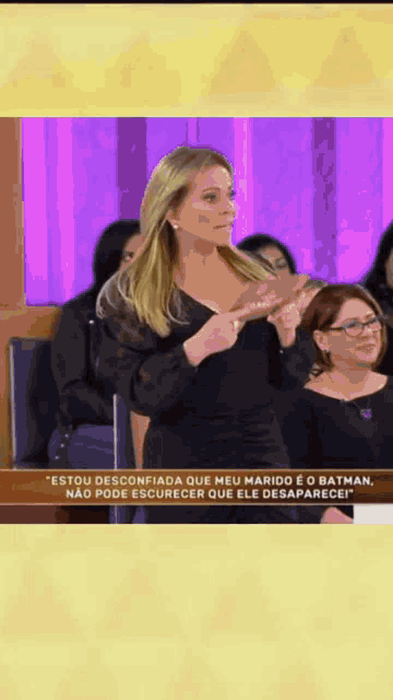 a woman in a black dress stands in front of a group of people and says estou desconfiada