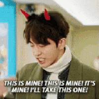 a man with devil horns on his head is wearing a turtleneck sweater and a green jacket .