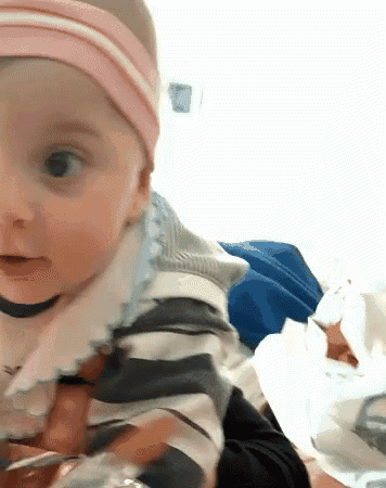 a baby wearing a pink headband is looking at something