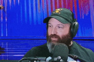 a man with a beard is wearing headphones and a hat with a skull on it .
