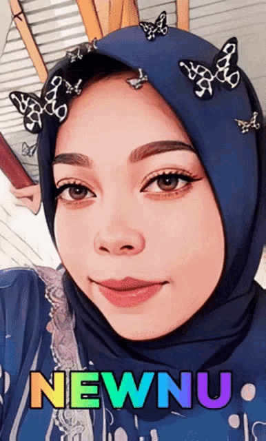 a woman wearing a blue hijab with butterflies on her head and the words newnu written below her