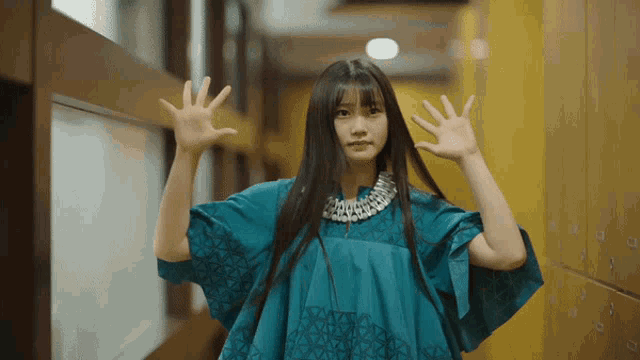 a woman in a blue dress is standing in a hallway with her hands outstretched