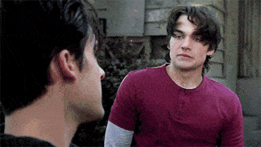 a man in a red shirt is looking at another man