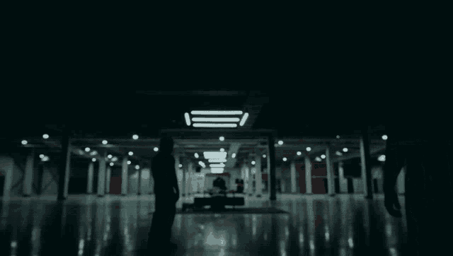 two people are walking through a dark hallway with a red door