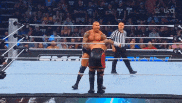 two wrestlers are in a wrestling ring with a referee standing behind them
