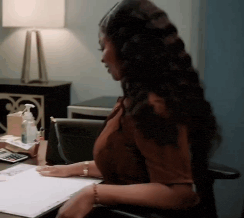 a woman is sitting at a desk with a calculator and a pen .