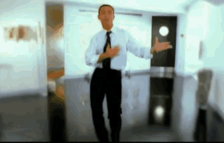 a man in a white shirt and black tie is standing in a hallway with his arms outstretched