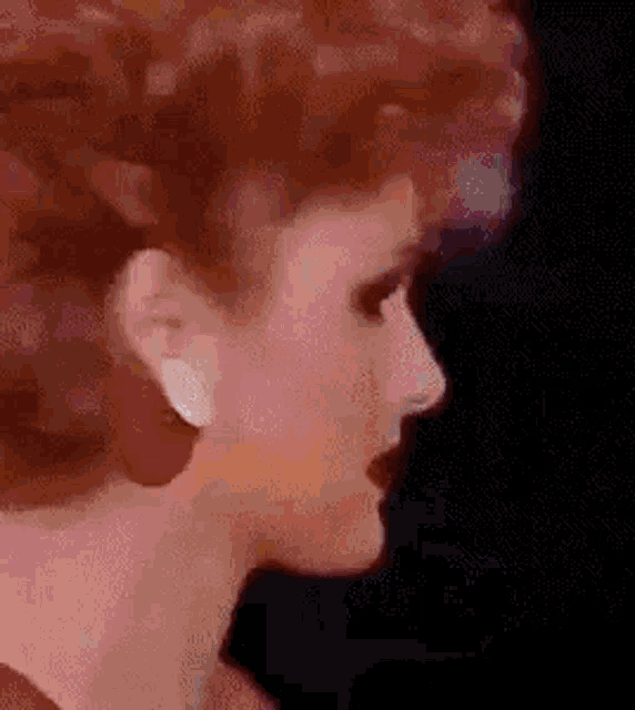 a close up of a woman 's face wearing red earrings and a red dress .