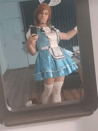 a woman in a maid costume is taking a picture of herself in a mirror