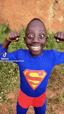 a young boy in a superman costume flexing his muscles