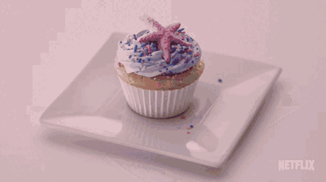 a cupcake with a starfish on top is on a white plate that says netflix on it