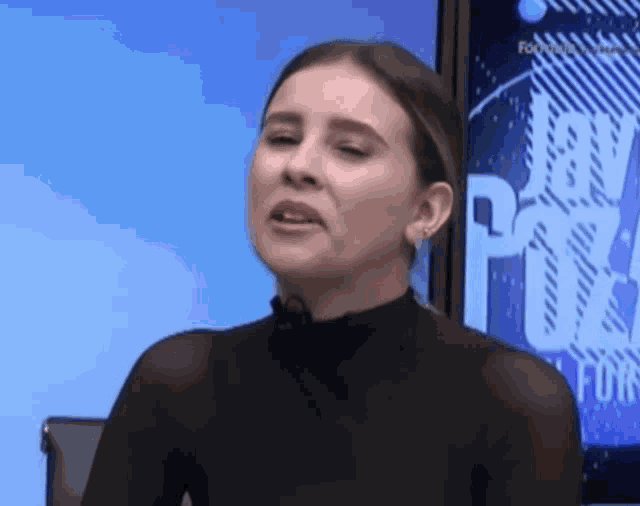 a woman in a black top is sitting in front of a television screen .