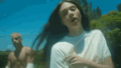a man without a shirt is standing behind a woman with long hair