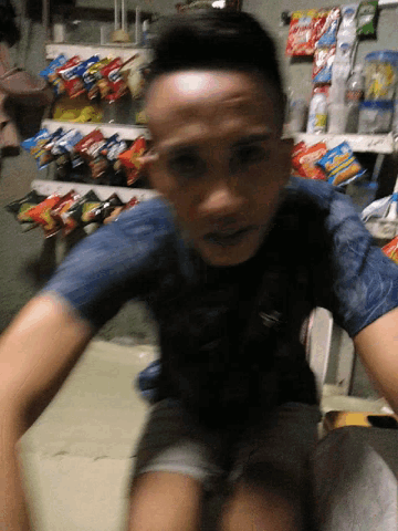 a man is standing in front of a shelf full of snacks including lays chips