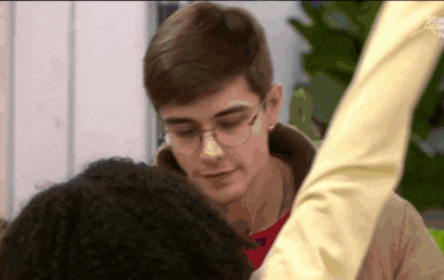 a man wearing glasses and a red shirt is looking at a woman 's face