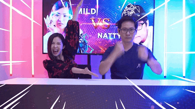 a man and a woman are standing in front of a tv screen that says mild vs natty