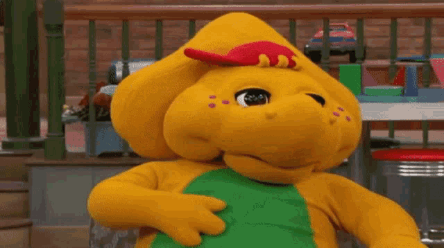 a stuffed dinosaur with a red hat and green shirt
