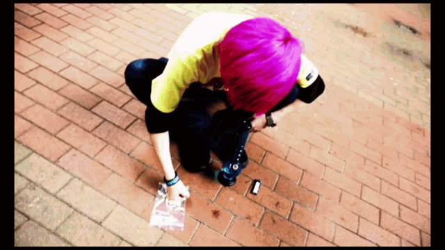 a person with pink hair is kneeling down on the ground
