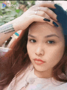 a woman with a tattoo on her wrist holds her hand to her forehead in front of a screen that says gocut on it