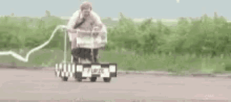 a man is riding a toy car on the road .