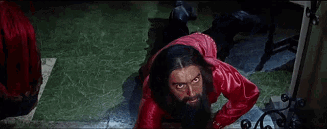 a man with a beard and a red shirt is crawling on the floor