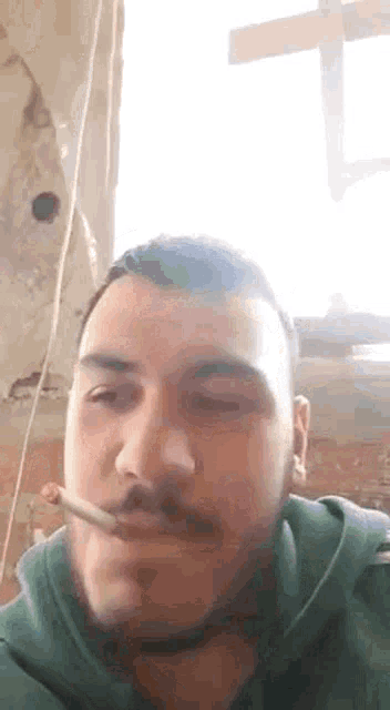 a man with a mustache is smoking a cigarette .