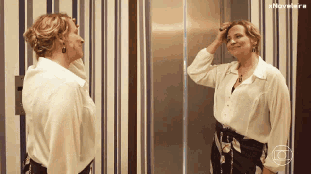 a woman adjusts her hair in front of a mirror with the words xnovelaira on the bottom